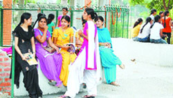 Girls interact with each other on the first day of opening of colleges after summer vacations in Amritsar