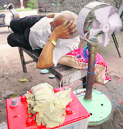 A battery operated fan provides respite to a shopkeeper during prolonged power cuts in Ludhiana.