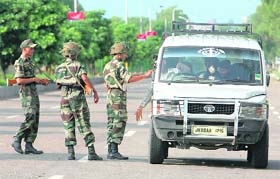 Army jawans stop a vehicle for checking during a curfew in Jammu