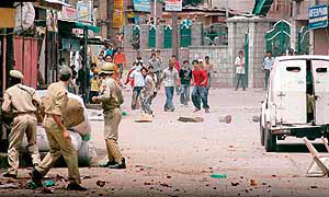 Protesters run after policemen fired tear gas shells during a strike in Srinagar on Monday.