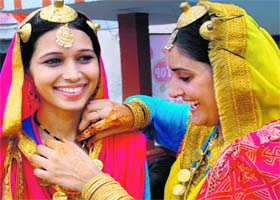 A participant gives final touches to her teammate’s costume at the 5th Teej Mela at Swami Vivekananda Girls College in Bathinda