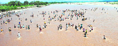 With the one-way bridge to Jammu under siege by the Army, demonstrators cross the Tawi river to join protests over Amarnath land issue in Jammu on Wednesday.