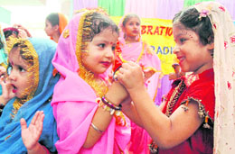 Tiny tots of Kiddies Paradise help each other wear bangles on the occasion of Teej in Ludhiana.