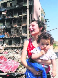 A Georgian woman holding her baby cries in agony as she sees her damaged home in Gori