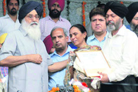 Punjab Chief Minister Parkash Singh Badal honours the parents of singer Ishmeet Singh; and (right) a contingent of the PAP takes part in a parade at a state-level function in Ludhiana on Friday.