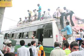 A private bus conductor collects ticket money on the top of a bus in Hisar