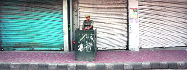 A Central Reserve Police Force soldier stands guard in front of closed shops during a protest in Jammu on Saturday. 