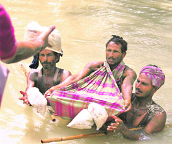 Villagers collect food packets as they wade through flood-affected areas in Laxmipur, about 400-km north-east of Patna on Wednesday.