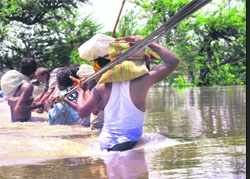 People wade through floodwaters with the help of a rope to safer places in Supaul district of Bihar on Wednesday.