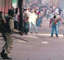 A CRPF jawan hurls a stone back at protesters in Srinagar on Friday.