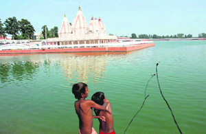 Two young boys throw magnet to find coins in Braham Sarover in Kurukshetra.