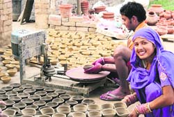 A woman lends a helping hand to her husband to make Diwali diyas in Ludhiana