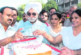 Gurbachan Singh, president, Nationalist Congress Party, Chandigarh unit, (centre), distributes a cake on the occasion of ‘Chandigarh Day’ at Sector 17