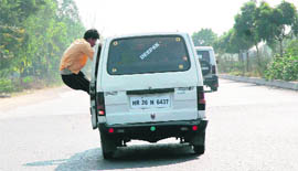 Not perturbed by the consequences, an attendant of an illegal taxi plying between Panipat and Sonepat travels by clinging to the door of the vehicle to make room for extra passengers.