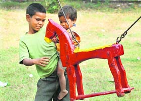 Two siblings look at a wooden horse with longing, oblivious of Children’s Day on Friday
