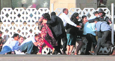 People duck as gunshots are fired from inside the Taj Mahal hotel in Mumbai on Thursday.