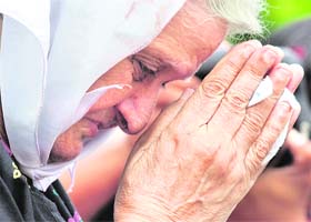 An elderly woman prays for victims of the Mumbai terror attacks in front of the Taj Mahal Hotel in Mumbai