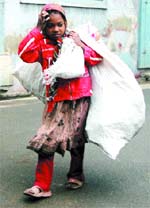 A girl ragpicker lost in a thought while carrying a bag on her shoulders in Amritsar on Friday.