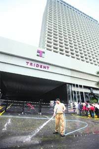 A worker cleans the road in front of the Trident-Oberoi hotel in Mumbai