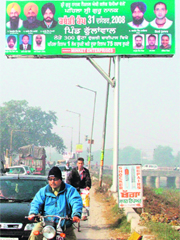 A poster of the forthcoming kabaddi cup eclipses a signpost showing directions to motorists in Ludhiana.