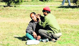 A man gets his ears cleaned while enjoying the winter sun in Gandhi Park in Dehradun