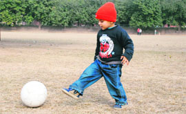 A kid plays football on a sunny afternoon at Panjab University on Monday.