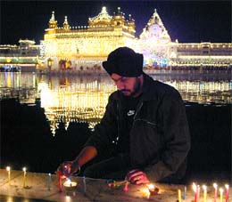 A Sikh devotee lights a candle on the occasion of Gurpurb at the Golden Temple in Amritsar on Monday