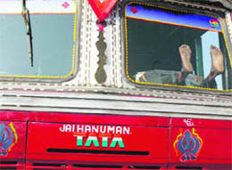 A driver relaxes with a newspaper in the cab of his truck parked on the outskirts of Hyderabad on Wednesday.