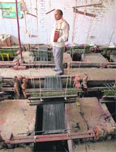 Anish Ahmed walks past pit looms at his unit in Panipat, which has been closed for two months