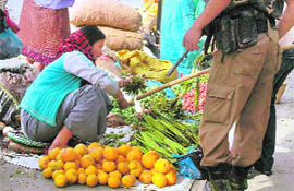 Policeman evicts a woman vegetable vendor in a market after the curfew relaxation time elapsed in Imphal on Sunday.