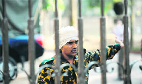 A Bangladesh Rifles soldier wears a white cloth around his head to signify surrender as he gestures through the gates of the headquarters in Dhaka on Thursday.