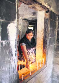 IN MEMORY: A riot victim lights a candle inside a burnt house in Ahmedabad