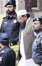 Hafiz Mohammed Saeed, in a whitecap, chief of Jammat-ud-Dawa, leaves under tight security after his court appearance in Lahore on Monday.