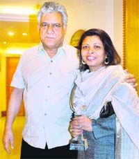 Author-Journalist Nandita Puri poses with the Woman Achievers Award along with her husband and Bollywood actor Om Puri on the occasion of International Women's Day