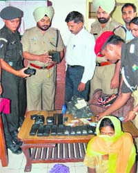 Police and Army officials inspect walky-talkies and Army uniforms confiscated from a woman (sitting) who was arrested by the RPF in Jalandhar