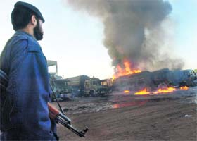 A Pakistani policeman watches burning tankers on the outskirts of Peshawar