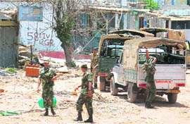 Lankan soldiers in front of destroyed buildings in Putumatalan, near the no-fire zone in northern Sri Lanka.