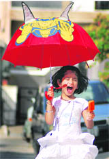 This little girl beats the heat with an ice candy and a chic Superman umbrella