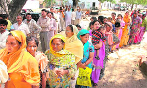 Voters stand in a queue to cast their vote in the Lok Sabha elections at Hoshiarpur on Wednesday.