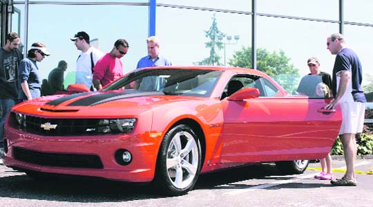 Patrons of an antique car show, which featured cars from General Motors past, present, and future, look at a newly released 2010 Chevrolet Camaro SS at the Sport Chevrolet dealership in Silver Spring, Maryland