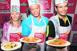 Legendary US athlete Maurice Greene (C) with model-actor Milind Soman and Ukranine athlete Inna Lebedevatry at a pasta-cooking event, ahead of the World 10K Marathon in Bangalore