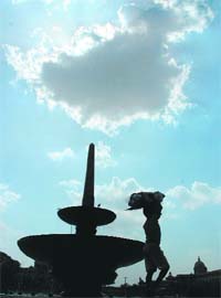 ARE THESE MONSOON CLOUDS? A young boy with his baggage gets a momentary respite from the scorching heat as sun plays hide and seek with the clouds in New Delhi