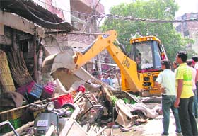 A JCB machine removes encroachments during anti-encroachment drive in old Sabzi Mandi, Ludhiana