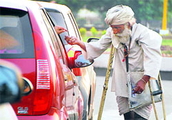 A beggar seeks alms at a traffic-light junction in Chandigarh on Sunday. The Chandigarh Administration has put a ban on begging but the practice goes on unabated.