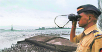 A policeman surveys the coastline as the Met department warned of a cyclone and heavy rain in Mumbai