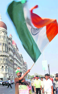 A man waves the Tricolour in front of the Taj hotel on the first anniversary of the 26/11 terror attacks in Mumbai on Thursday.