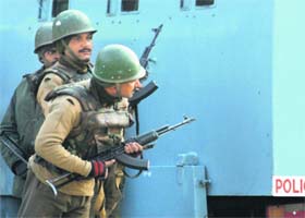 CRPF jawans take position behind an armed vehicle where suspected militants are holed up in a hotel at Lal Chowk in Srinagar