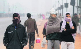 People take full protection against cold wave on a foggy and chilly morning at India Gate in New Delhi.