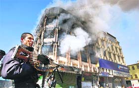 An Afghan policeman stands in front of the shopping mall in Kabul, where Taliban gunmen battled security forces for hours