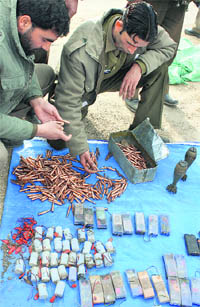 Security personnel display a huge cache of arms and ammunition, including 10 kg of RDX and 108 grenades, at Pattan on Saturday.